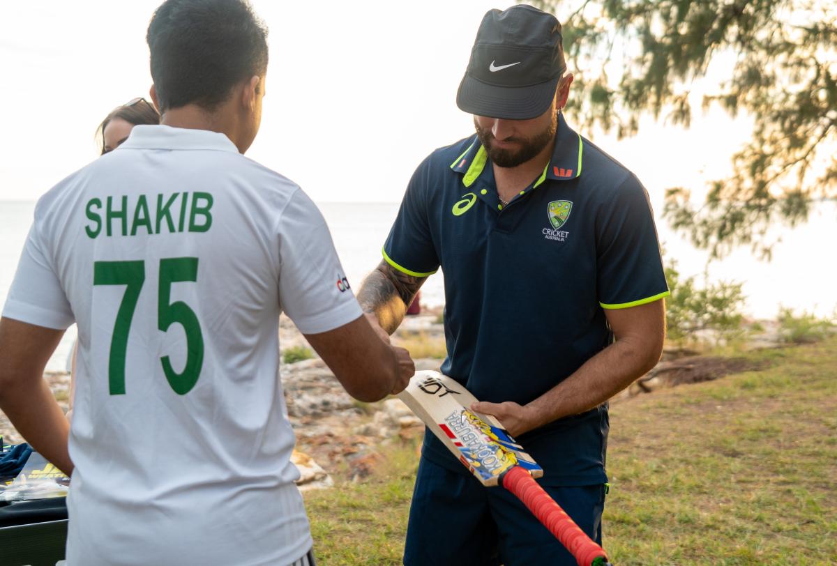A Cricket player signs a fan's bat