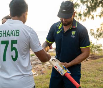 A Cricket player signs a fan's bat
