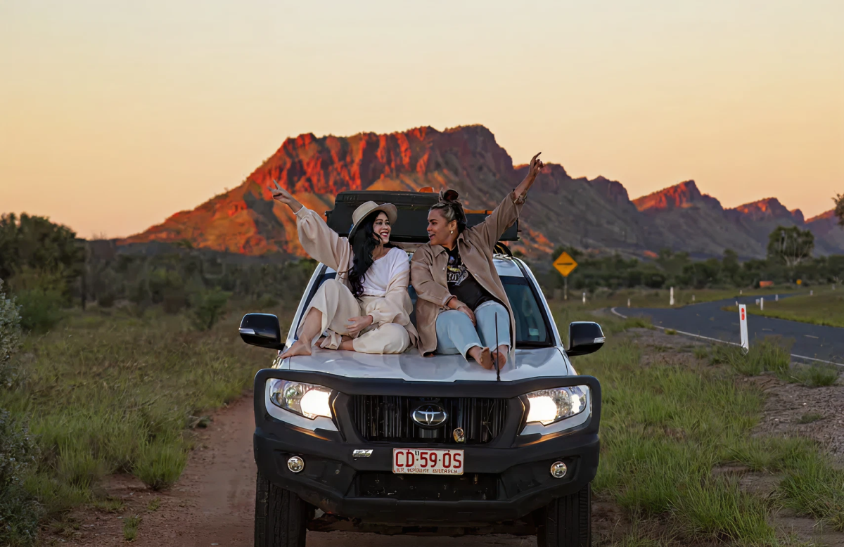two ladies sitting on the bonnet of a 4 wheel drive vehicle in the Australian Outback